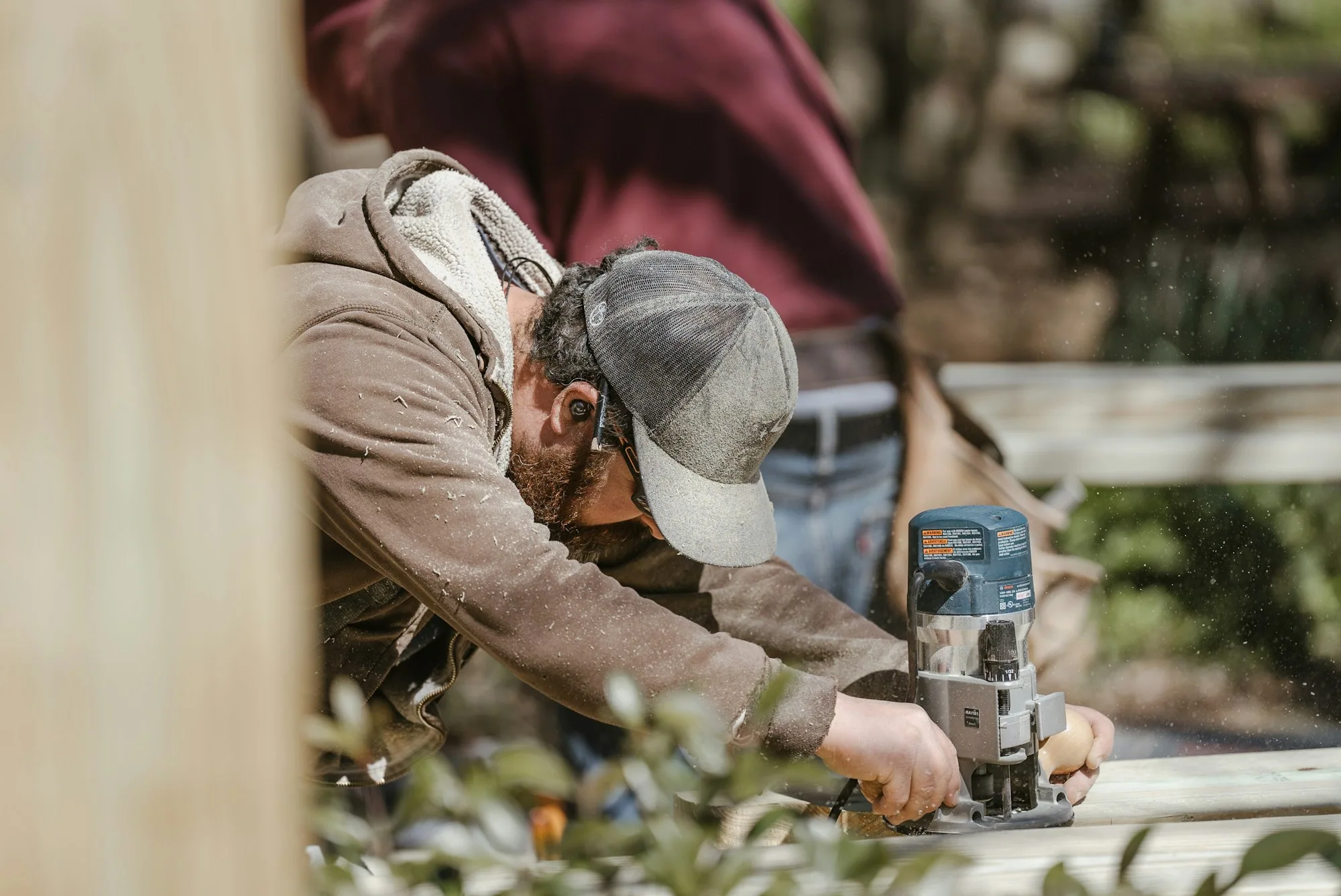 Carpenter using a router on a board outdoors